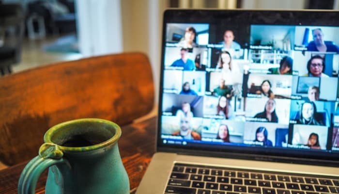 Larger Zoom meeting on a Laptop with mug next to the laptop