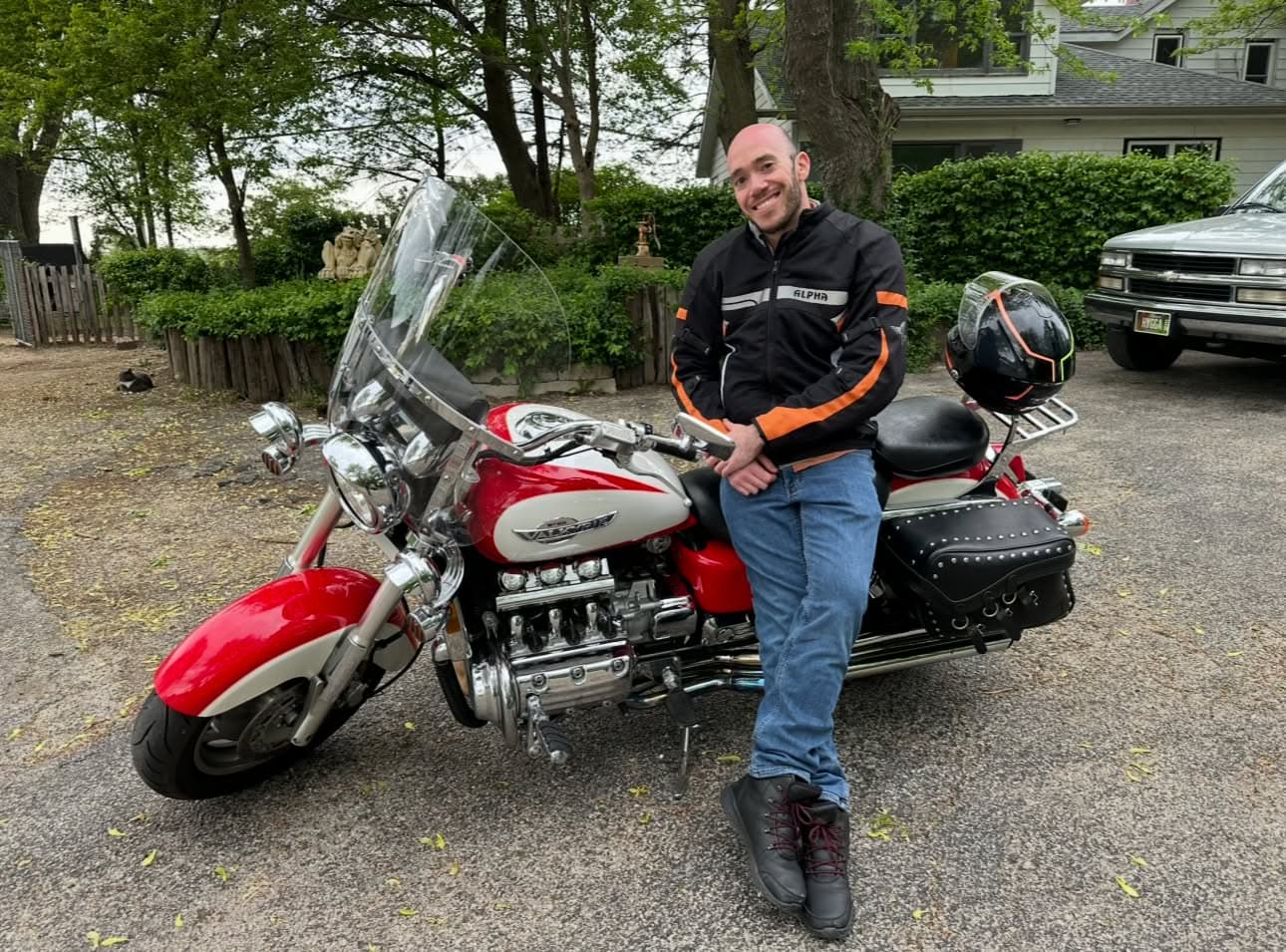 Man sitting on red cruiser motorcycle outdoors